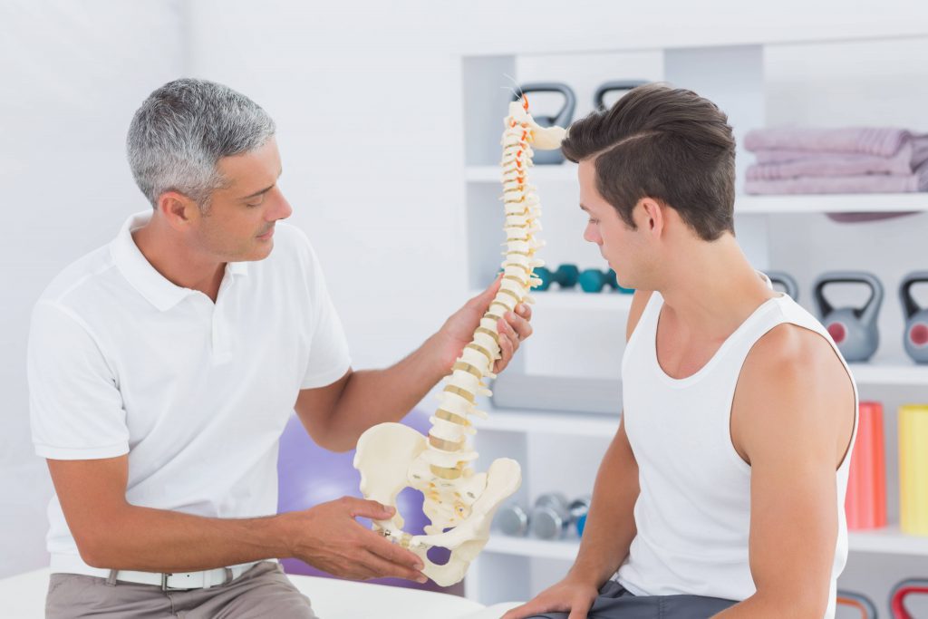 chiropractor-showing-anatomical-spine-to-his-patient